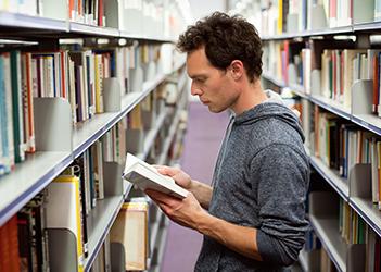 UB student reading a book in the library